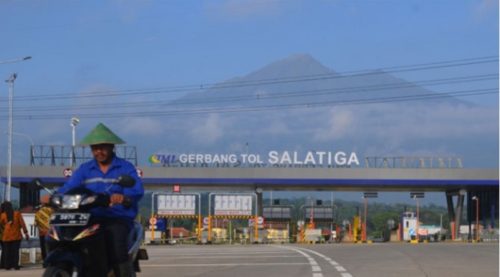 Warga melintas dekat gerbang tol Salatiga yang berlatar belakang gunung Merbabu di Tingkir, Salatiga, Jawa Tengah.